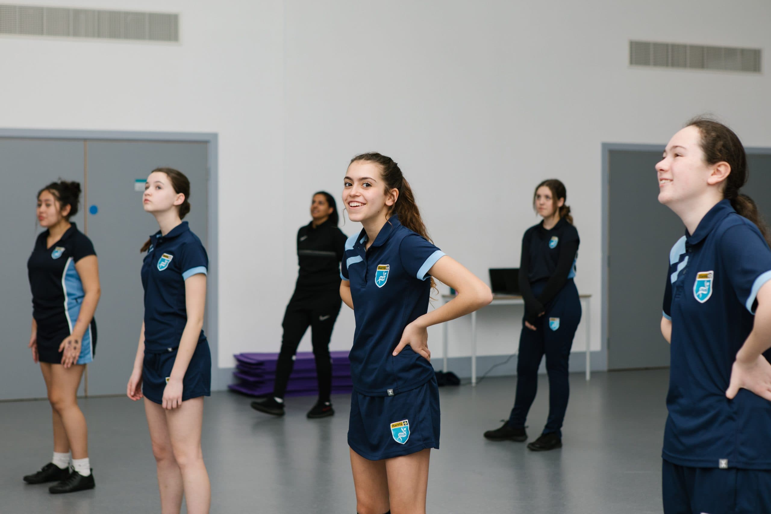 A teenage girl smiling at the camera within a PE lesson