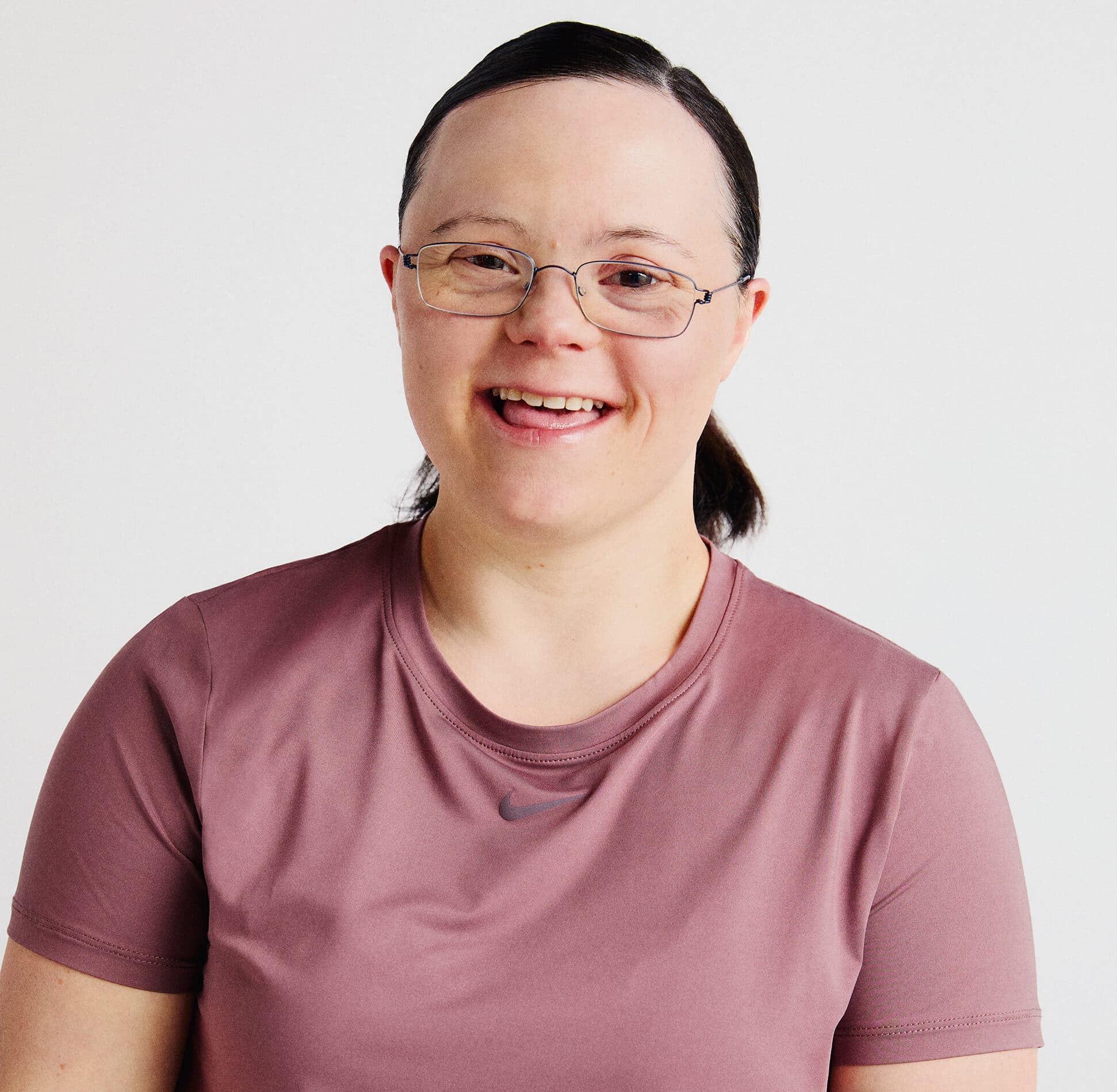 An image of Disability Sports Coach trainer, Caitlin. A woman with dark brown hair in a pony tail, wearing a pink short sleeved tshirt