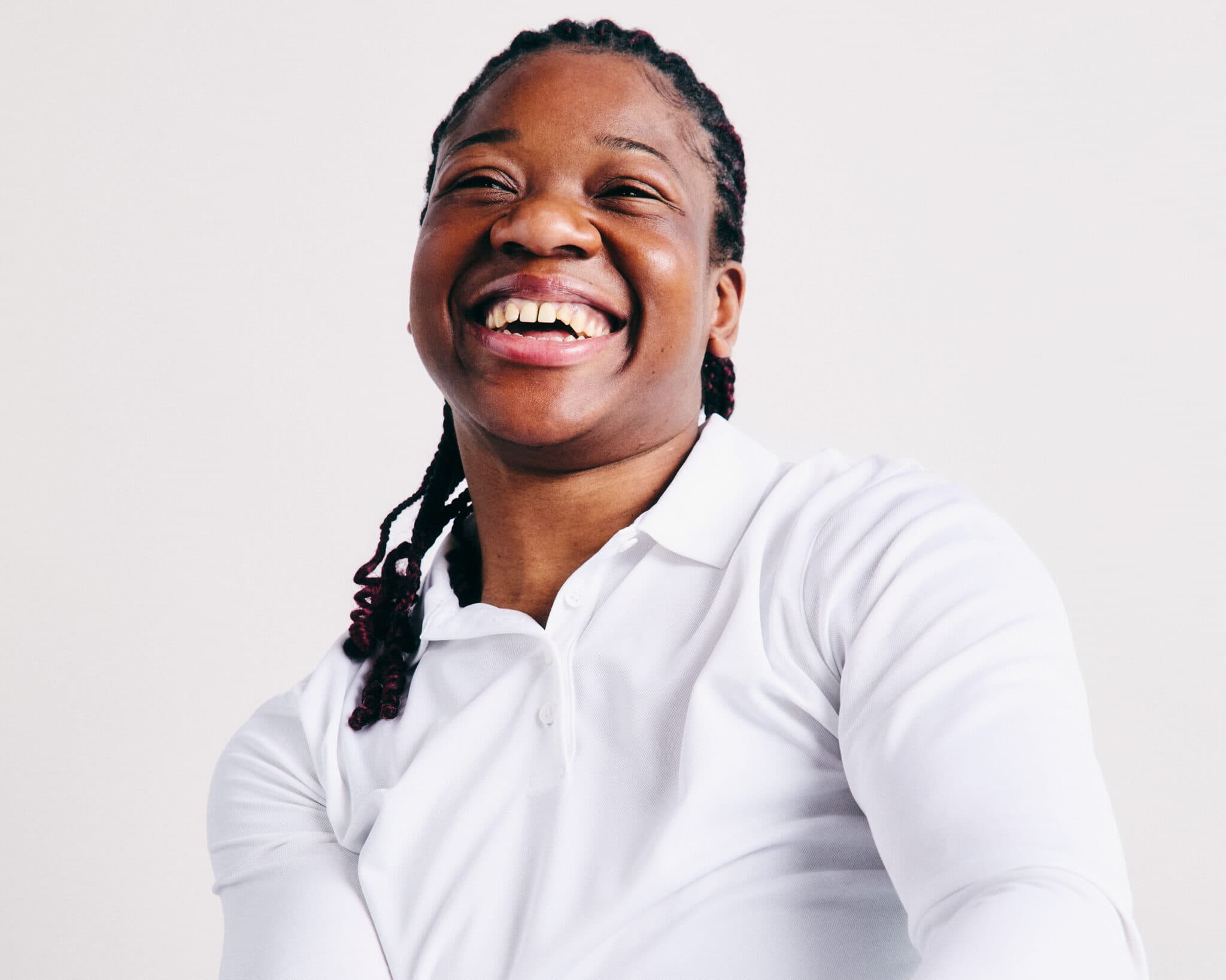 An image of Disability Sports Coach, Marie. A woman with black braided hair, wearing a white long sleeved top