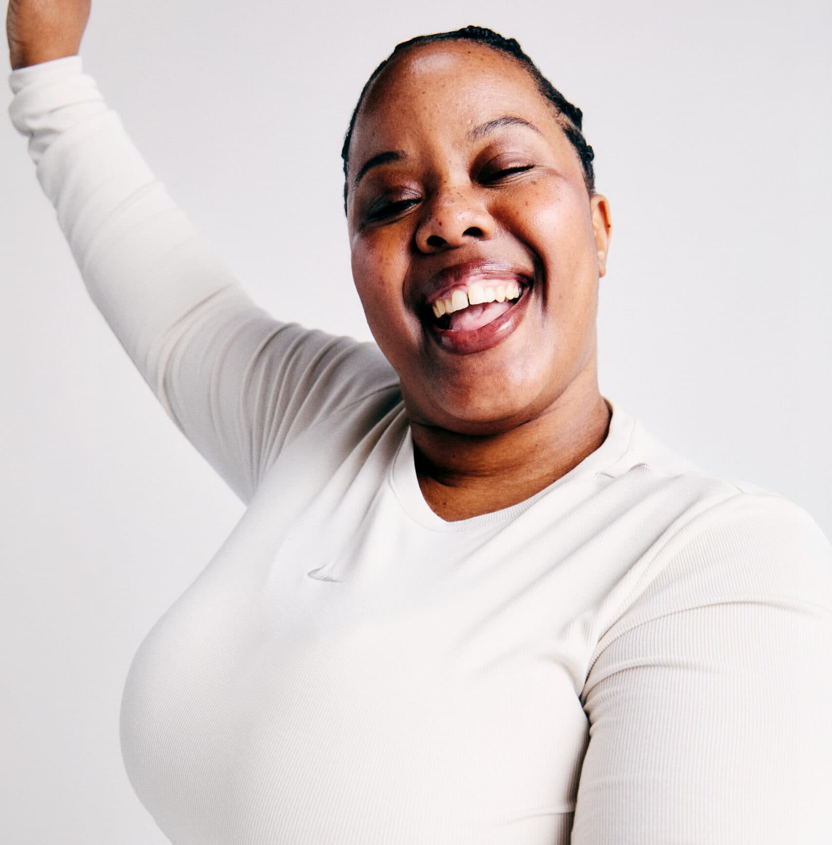 An image of dance trainer, Trina. A woman with dark brown hair braided, wearing a cream long sleeved top